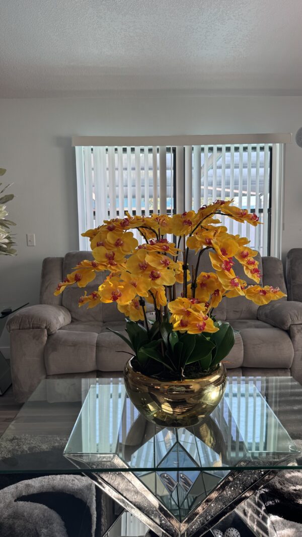 Cascading yellow orchids, gold-colored stainless steel vase